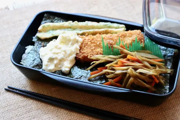A delicious nori bento box with fried fish, creamy potato salad, and stir-fried vegetables.